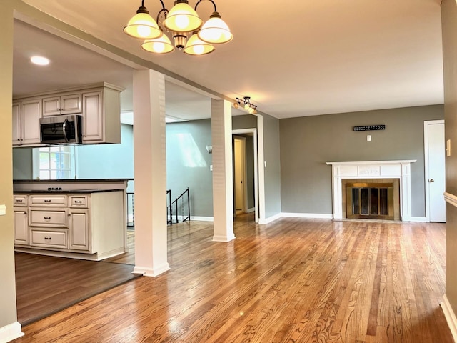  - unfurnished living room with wood finished floors, a chandelier, and a fireplace with flush hearth