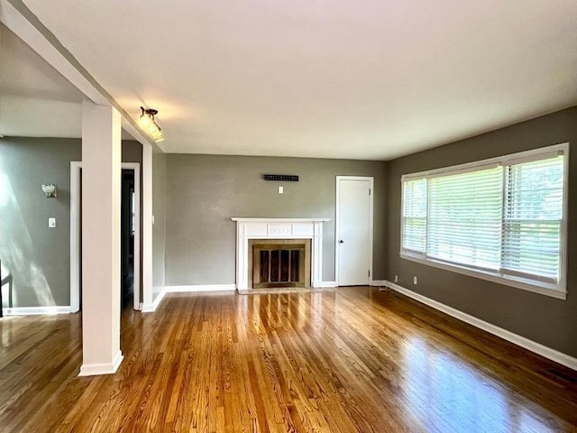  - unfurnished living room featuring wood finished floors and a glass covered fireplace