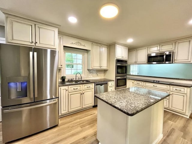  - kitchen with stainless steel appliances, light wood finished floors, cream cabinets, a center island, and recessed lighting