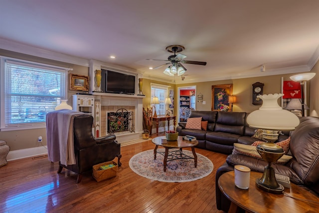 living room featuring a fireplace, hardwood / wood-style flooring, crown molding, and ceiling fan