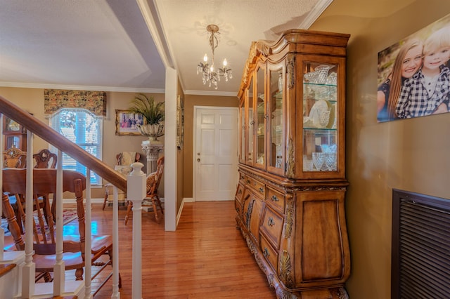 foyer entrance featuring light hardwood / wood-style flooring, a chandelier, and ornamental molding