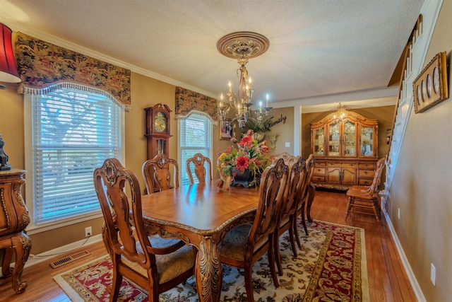 dining space with a textured ceiling, ornamental molding, a notable chandelier, and dark hardwood / wood-style flooring