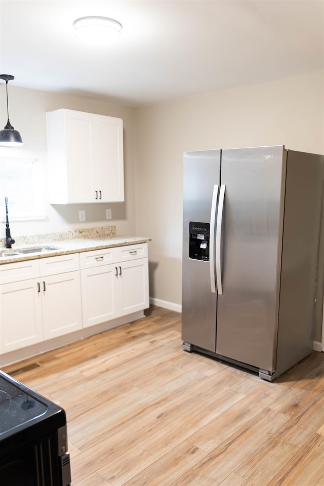 kitchen with stainless steel refrigerator with ice dispenser, sink, white cabinetry, decorative light fixtures, and light wood-type flooring