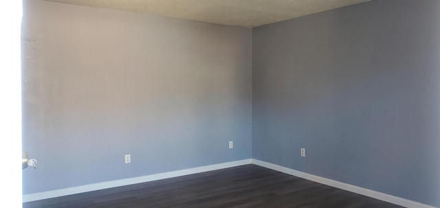 unfurnished room with dark wood-type flooring and a textured ceiling