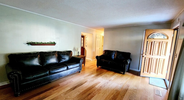 living room with light hardwood / wood-style floors, ornamental molding, and a textured ceiling