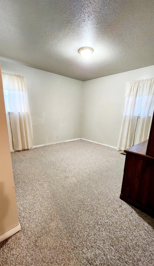 carpeted spare room with a textured ceiling