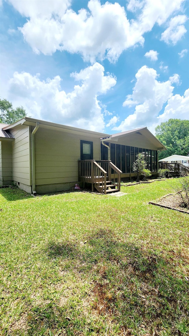 rear view of house featuring a sunroom and a lawn