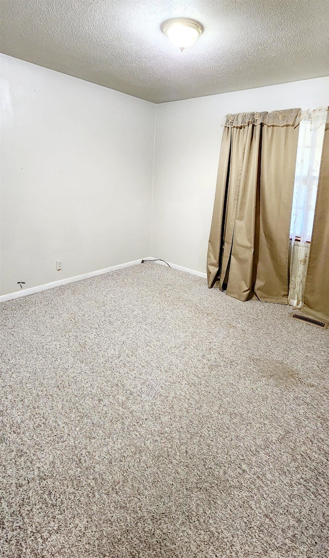 carpeted empty room featuring a textured ceiling