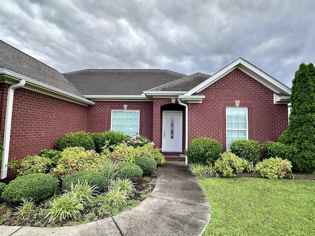 - view of front of home featuring brick siding, roof with shingles, and a front lawn