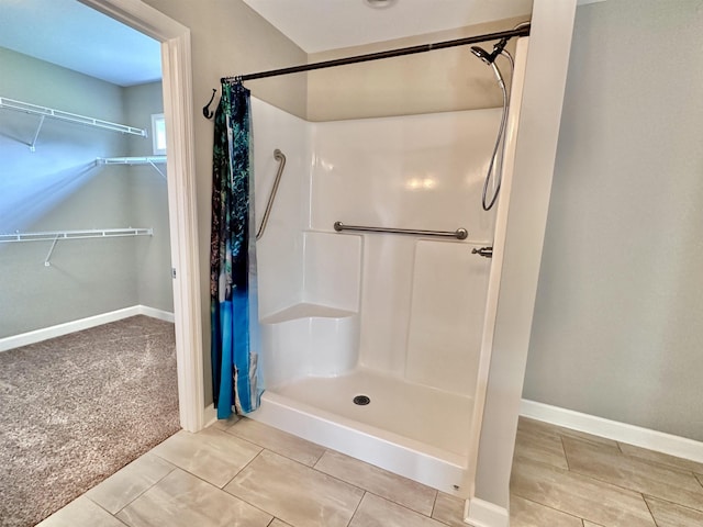  - bathroom with a shower, baseboards, a spacious closet, and tile patterned floors