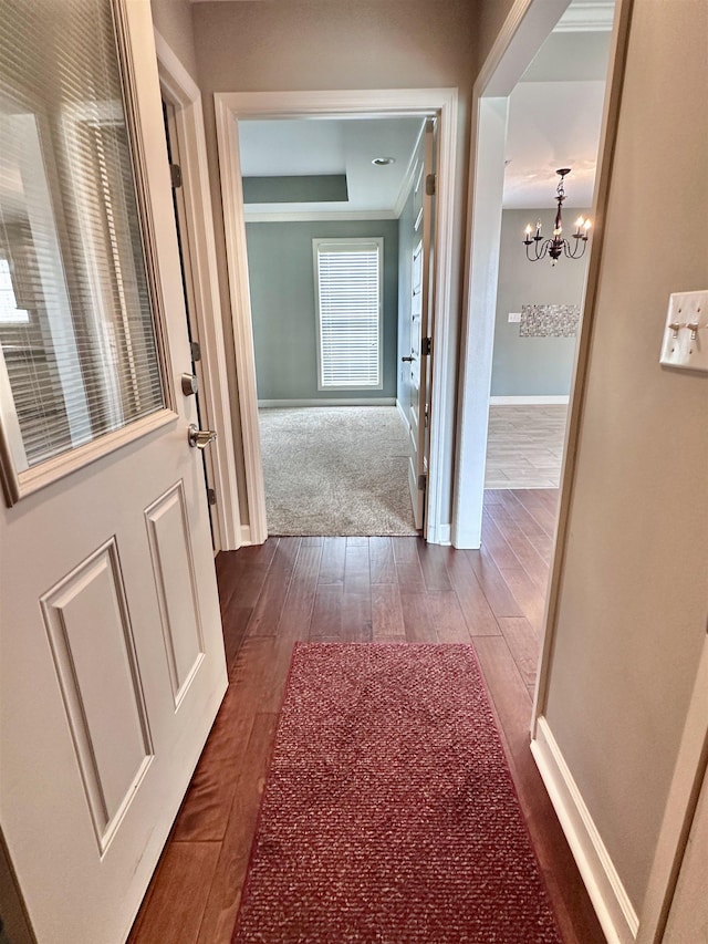  - hallway featuring a chandelier, dark wood finished floors, baseboards, and a raised ceiling