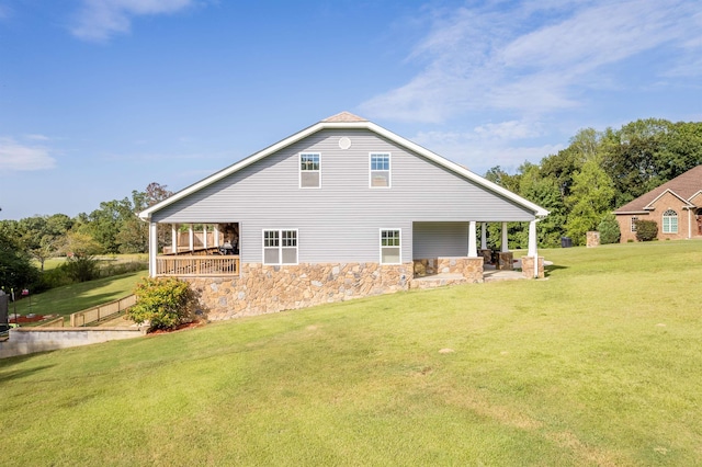 rear view of house featuring a patio area, a lawn, and stone siding