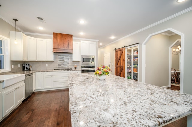 kitchen featuring dark wood-style floors, white cabinetry, stainless steel appliances, and a barn door