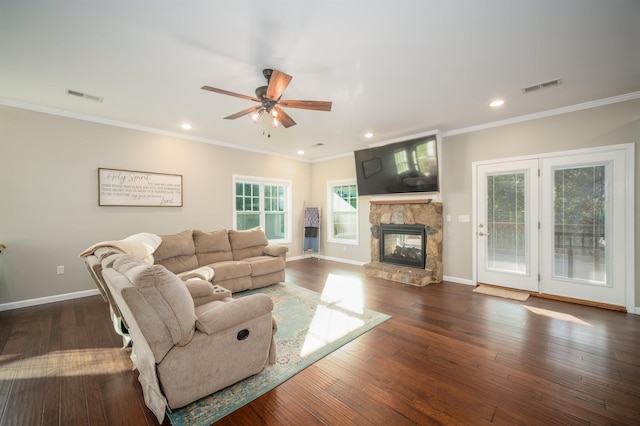 living room with visible vents, baseboards, a stone fireplace, and hardwood / wood-style flooring