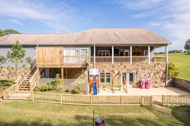 back of property with stairway, a lawn, a shingled roof, and a patio