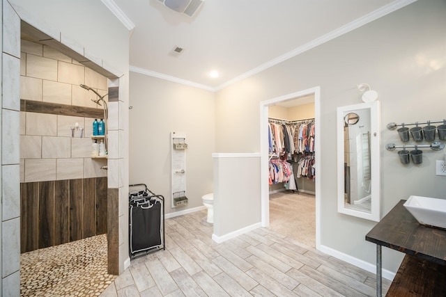 bathroom featuring wood finished floors, baseboards, a walk in shower, crown molding, and toilet