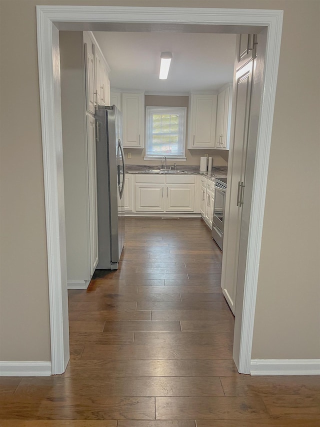 kitchen featuring stainless steel appliances, white cabinetry, dark wood-type flooring, and sink