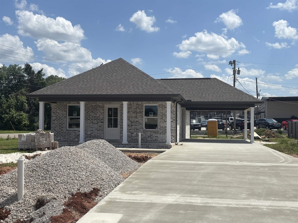  - single story home featuring a porch, concrete driveway, a shingled roof, and brick siding