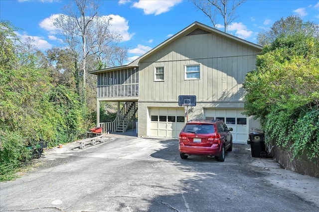  - view of home's exterior with stairway, an attached garage, concrete driveway, and a sunroom