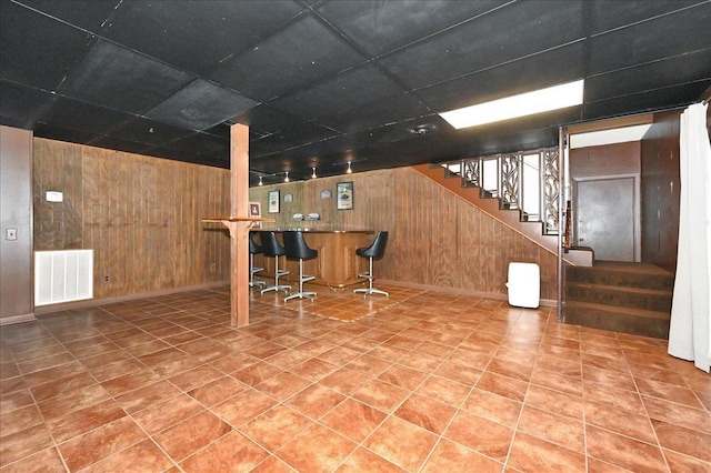  - bar with visible vents, wood walls, stairs, tile patterned floors, and a dry bar
