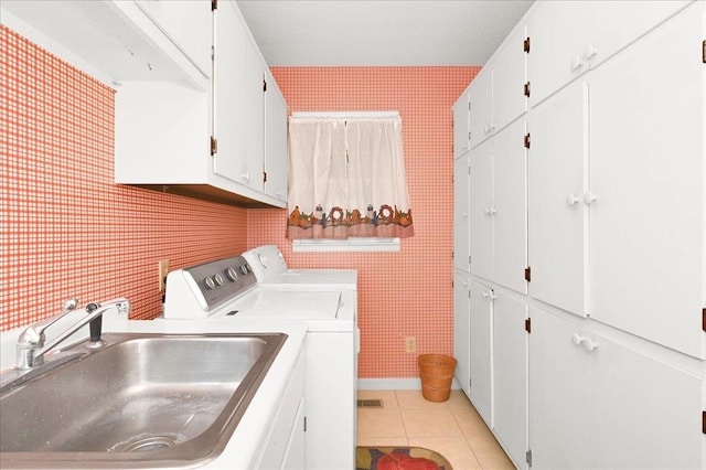  - clothes washing area with washing machine and clothes dryer, cabinet space, a sink, light tile patterned floors, and wallpapered walls