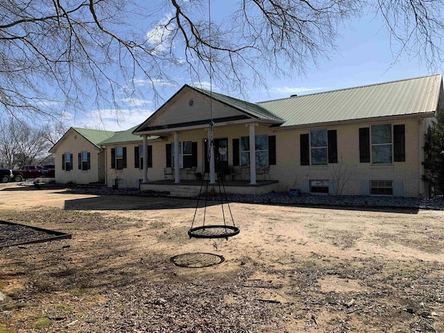 rear view of property featuring metal roof and brick siding