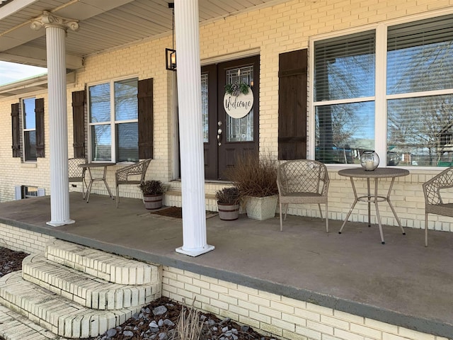 entrance to property featuring covered porch and brick siding