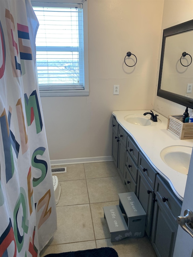 full bathroom with double vanity, tile patterned flooring, a sink, and baseboards