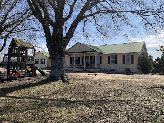 rear view of property featuring an outdoor fire pit, metal roof, and a playground