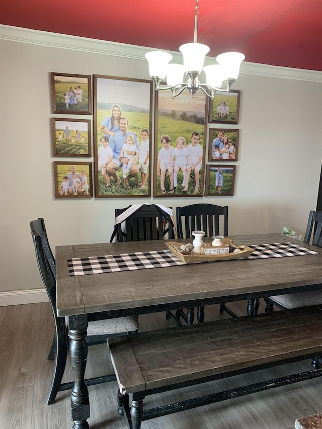 dining room with an inviting chandelier, crown molding, baseboards, and wood finished floors