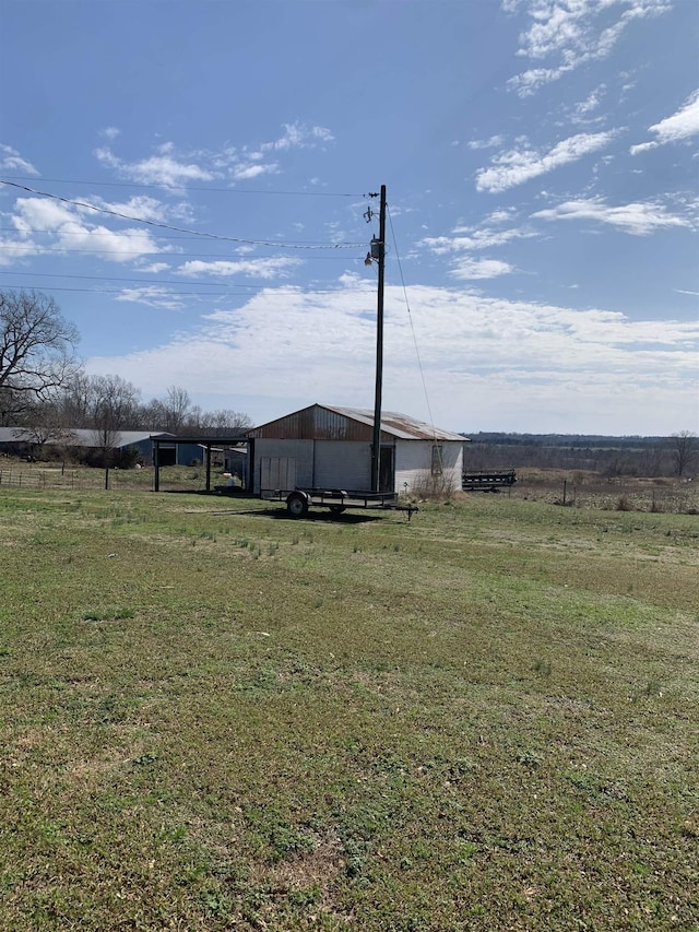 view of yard featuring a pole building, a rural view, and an outdoor structure