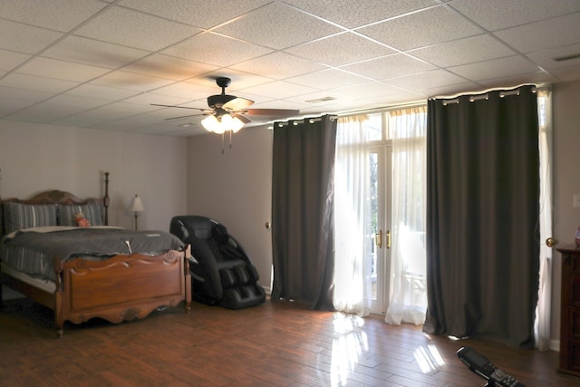 bedroom featuring a drop ceiling, hardwood / wood-style floors, and ceiling fan