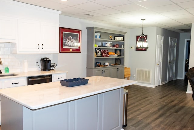 kitchen featuring dishwasher, a center island, tasteful backsplash, a drop ceiling, and decorative light fixtures