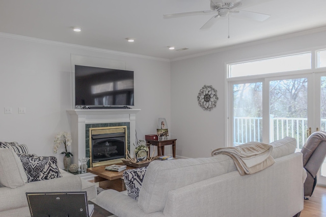 living room with crown molding, wood-type flooring, and a tiled fireplace