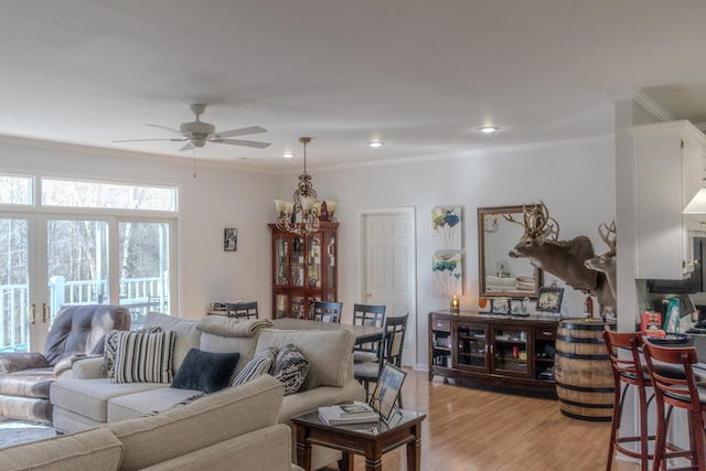 living room featuring crown molding, ceiling fan with notable chandelier, and light hardwood / wood-style floors