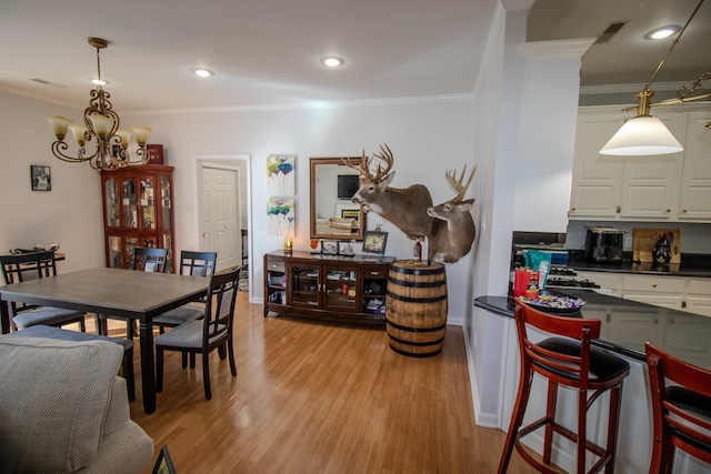 dining space featuring crown molding, a notable chandelier, and light wood-type flooring