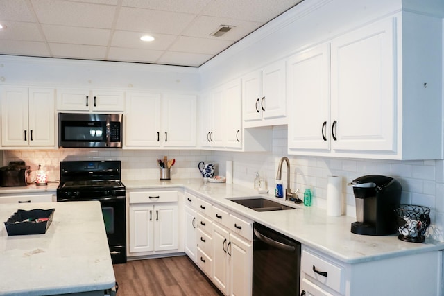 kitchen with sink, black appliances, a drop ceiling, dark hardwood / wood-style floors, and white cabinets