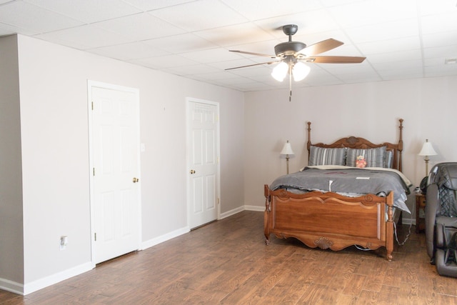 bedroom with ceiling fan, dark hardwood / wood-style flooring, and a drop ceiling