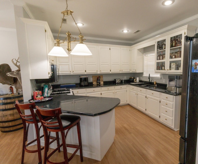 kitchen with white cabinetry, decorative light fixtures, sink, and stove