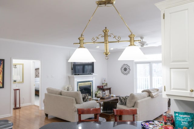 living room with ornamental molding, light wood-type flooring, and ceiling fan