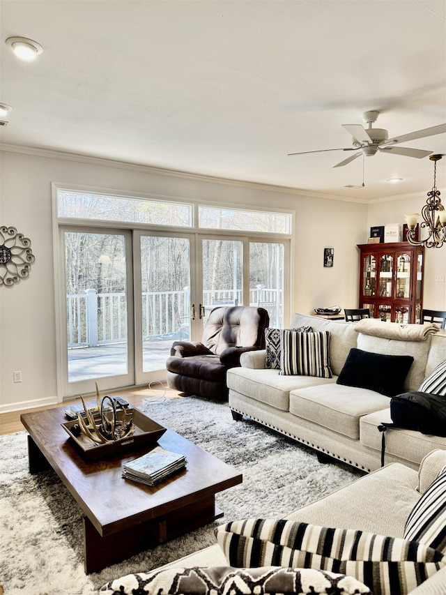 living room featuring ornamental molding, ceiling fan with notable chandelier, and light hardwood / wood-style floors