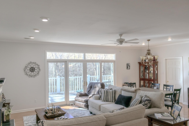 living room with ceiling fan with notable chandelier, light hardwood / wood-style flooring, and ornamental molding