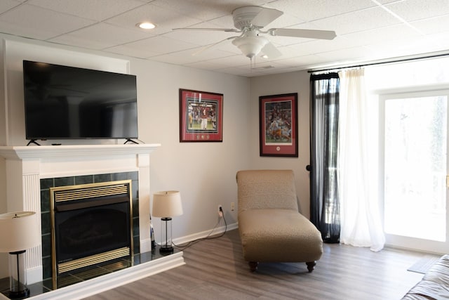 sitting room featuring a fireplace, wood-type flooring, ceiling fan, and a paneled ceiling