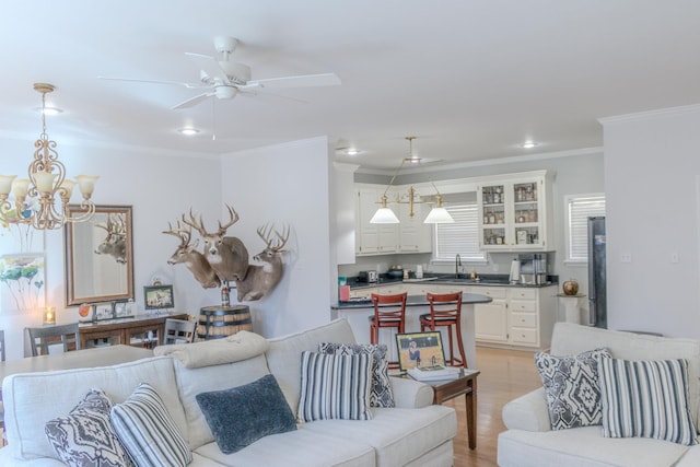 living room with ornamental molding, sink, ceiling fan with notable chandelier, and light hardwood / wood-style flooring