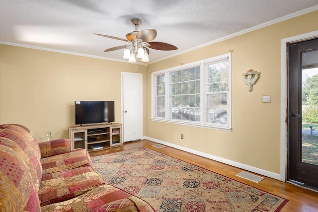 living room with ceiling fan, wood-type flooring, a textured ceiling, and ornamental molding