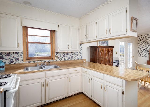 kitchen featuring kitchen peninsula, electric stove, white cabinetry, and sink