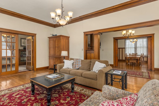 living room with baseboards, ornamental molding, wood finished floors, and a chandelier