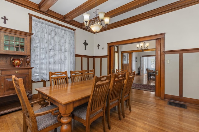 dining space featuring visible vents, beamed ceiling, a chandelier, light wood-style floors, and ornamental molding