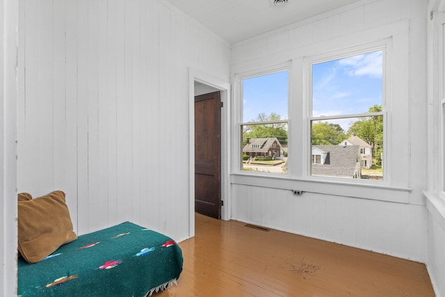 bedroom with crown molding, wooden walls, and wood finished floors