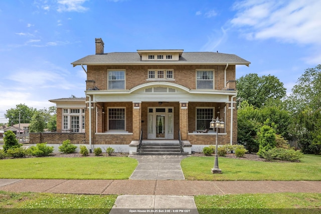 american foursquare style home with a chimney, a porch, a front lawn, and brick siding